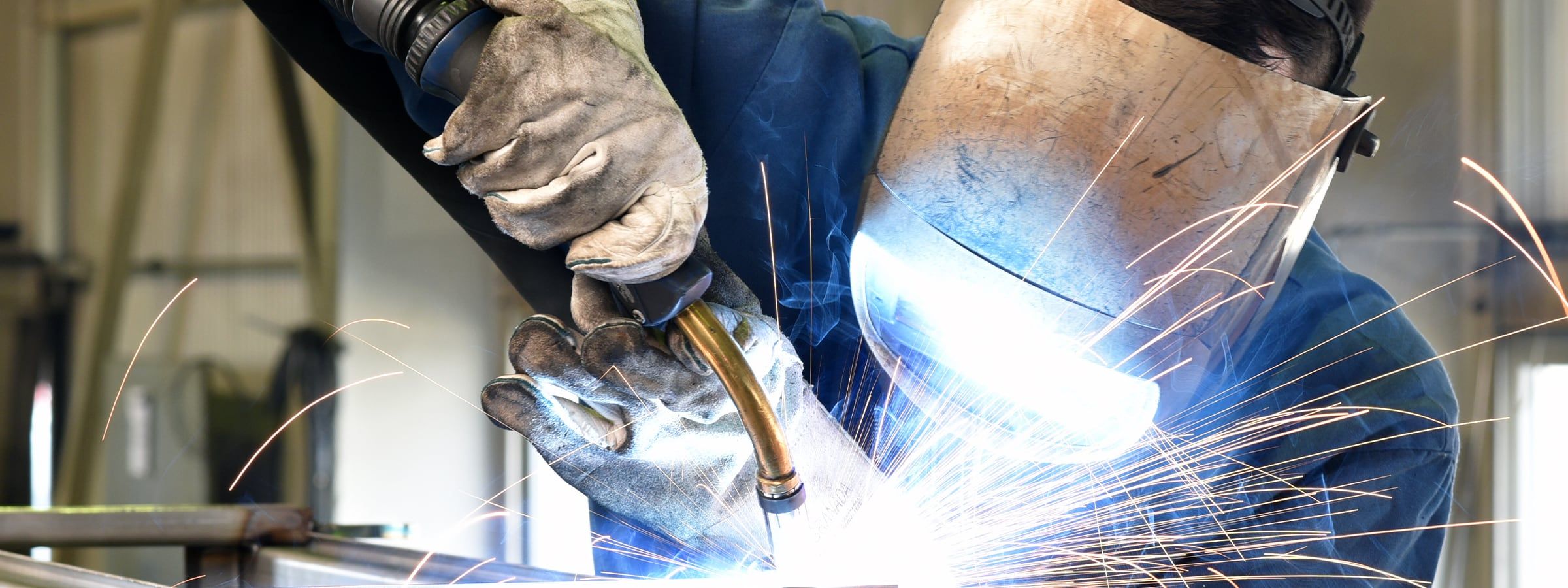 Schweißer im Schutzkleidung, Maske und Handschuhen schweißt Teile zusammen