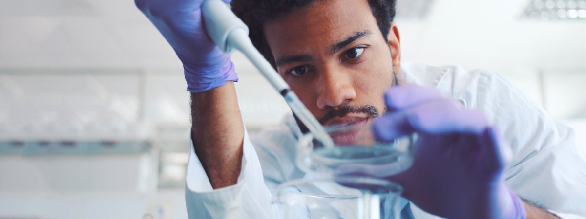 Ein Laborant nimmt mit einer Pipette eine Probe.