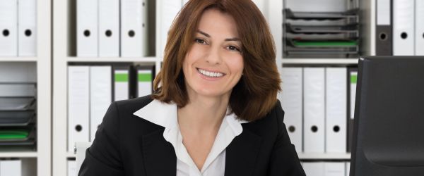 Buchhalterin arbeitet im Büro vor einer vollen Aktenwand